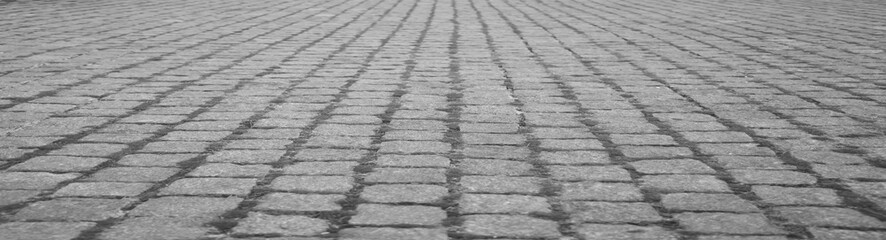 Old square cobble stone with green grass. paving perspective background.Paving stone pavement texture. Cobblestone pavement. stone sidewalk. texture. Cobble stone road cobble texture. perspective