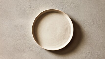 Top-down view of an empty beige ceramic plate with a textured surface on a neutral grey background.