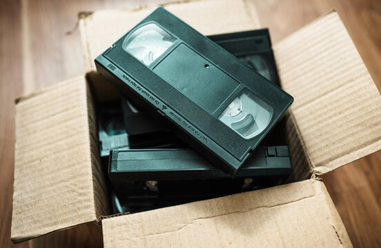 An old box with retro video cassettes on a floor.