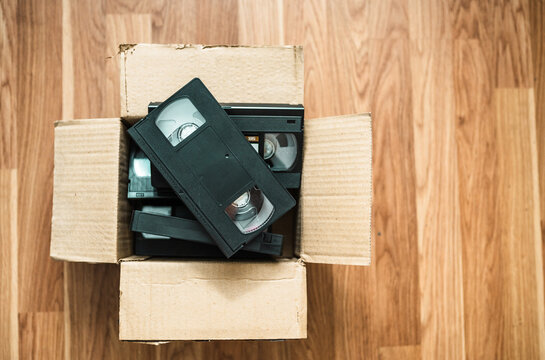 An old box with retro video cassettes on a floor.
