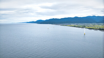 雨が降りそうな9月の富山県入善町沿岸からみる洋上風力発電風車をはじめとする様々なもの