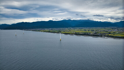 雨が降りそうな9月の富山県入善町沿岸からみる洋上風力発電風車をはじめとする様々なもの