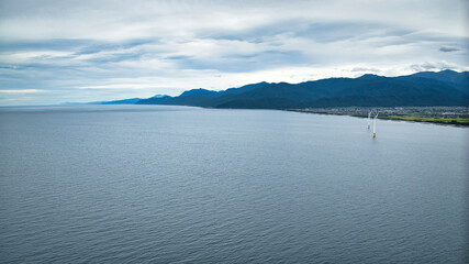 雨が降りそうな9月の富山県入善町沿岸からみる洋上風力発電風車をはじめとする様々なもの