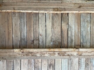 An intricate, high-angle shot of a rustic wooden ceiling or wall, featuring weathered planks arranged in a diagonal pattern and crossed by structural beams. This is perfect for designers needing a nat