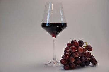 Close-up of wine glass with bunch of pink grapes
