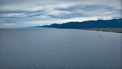 雨が降りそうな9月の富山県入善町沿岸からみる洋上風力発電風車をはじめとする様々なもの