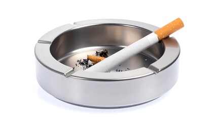 A full, metallic ashtray with cigarette and ash rests on a plain white background.
