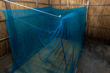 Reed-Walled African House with Blue Mosquito Net over Traditional Reed Mat
