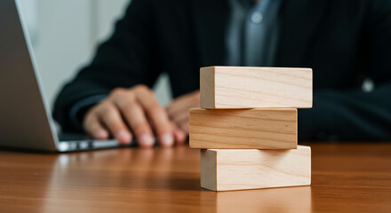 Crafting strategy A businessman with wooden blocks building success with a laptop in soft focus and