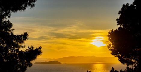 Tranquil Sunset Over Serene Ocean with Silhouetted Island and Lush Trees