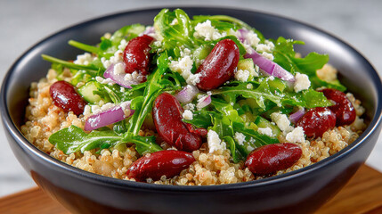 Fresh quinoa salad with greens and kidney beans in a black bowl.
