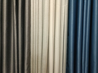 Obraz premium Gray curtain fabric, beige linen drape, white blackout curtain and blue satin curtain hung side by side creating calm textile display with subtle texture and soft folds