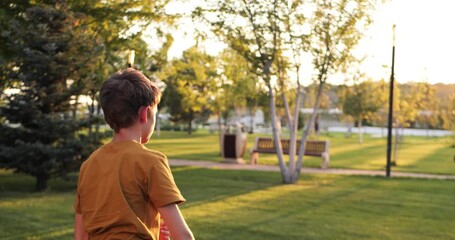 Boy throws rugby ball across park during golden hour. Boy steps forward and releases the ball with focus. Warm sunlight accentuates dynamic action and flying ball. youth sports and active outdoor play - Powered by Adobe