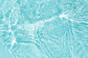 Blue water with ripples on the surface. Defocus blurred transparent blue colored clear calm water surface texture with splashes and bubbles. Water waves with shining pattern texture background.
