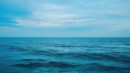 Obraz premium The blue ocean horizon under a cloudy sky, with calm waves gently rolling, has ample white space, creating a tranquil coastal atmosphere suitable for nature or creative projects.