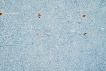 Close up surface of aged and weathered rusty metal surfaces in high resolution. Faded blue paint background with rust