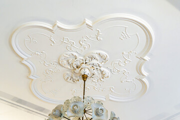 Round antique vintage decorative clay stucco relief molding with floral ornaments on white ceiling in abstract classical style interior