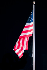 Flag of the United States of America on a flagpole at night