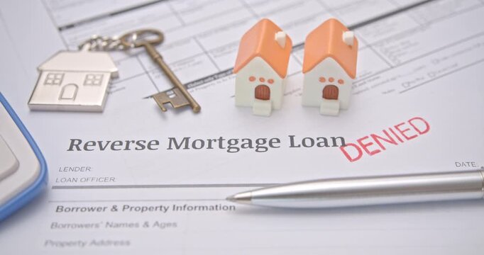Loan denial, reverse mortgage loan, denied mortgage, home loan refusal or rejection : A red 'DENIED' stamp on a Reverse Mortgage Loan application form, symbolizing loan rejection, financial risk, etc