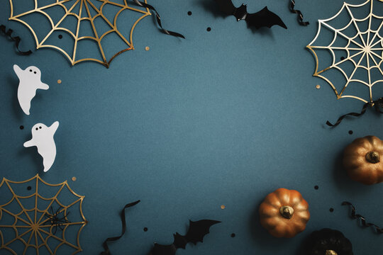 Halloween party frame from pumpkins, bats, spider web, ghosts on blue background top view.