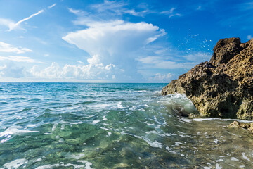 Waves crashing on rocky shoreline under a towering anvil cloud
