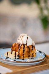 Honey Toast, a square toast baking with butter and topped with vanilla ice cream and chocolate sauce served with banana on blue plate.