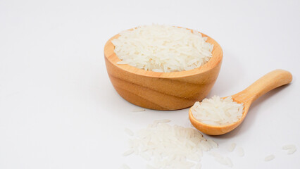 White rice grains in wooden bowl and spoon on white background