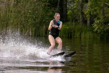 Fototapeta premium Young woman with charming smile goes water skiing on lake