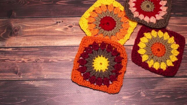 Crocheted samples handmade granny squares are falling on the wooden surface of table 