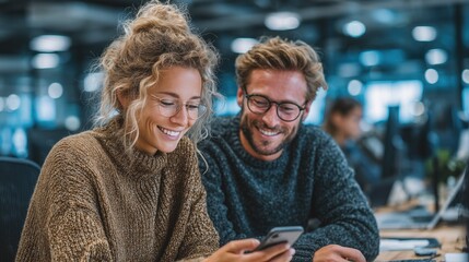 Smiling business colleagues, a woman and a man, looking at smartphone together in modern open office workspace, showing teamwork, collaboration, and positive workplace interaction.