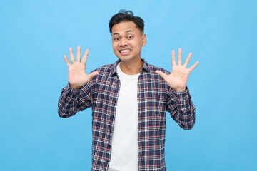 Young Asian man wearing casual clothes, counting or showing number ten with fingers, standing...