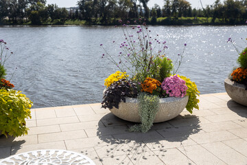 Colorful flower arrangement in stone planter by the riverside on a sunny day