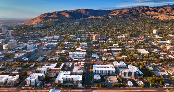 Lively green city scattered at the mountain foot. Drone footage above the cityscape of Salt Lake City, Utah, USA at sunset.