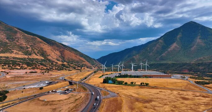 Footage over the deserted land with wind turbines rotating in the wind. Dramatic cloudscape over the rocks in Spanish Fork, Utah County, Utah, United States.