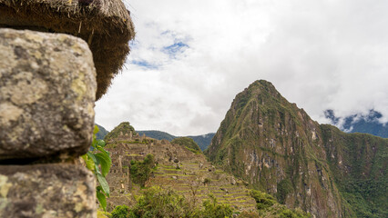 View of Machu Picchu ruins framed by an ancient Inca stone building