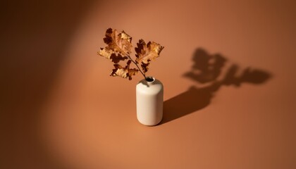 Minimalist autumn decor with dried leaves in ceramic vase on warm brown background. perfect for interior design concepts or seasonal aesthetic promotions