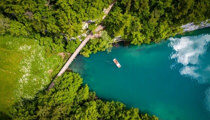 High-angle view of a turquoise lake, a wooden bridge, and lush forest