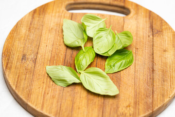 Fresh Green Basil Leaves on Wooden Cutting Board in Kitchen