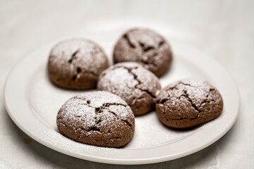 Fresh Baked Chocolate Cookies with Powdered Sugar Topping on White Plate