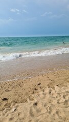 A serene beach scene with golden sand and gentle waves lapping at the shore. Clear blue water meets the sky, creating a peaceful atmosphere with ample copy space.