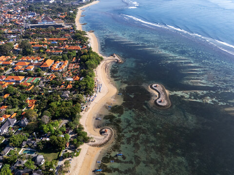 Sanur beach, Bali, Indonesia, September 01, 2025: Aerial view of pantai karang  with sandy coastline, resorts, boats, and small stone jetties surrounded by turquoise sea and coral reefs.
