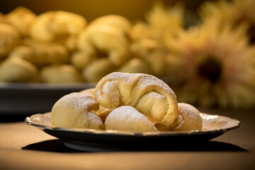 Homemade pastries - a handmade yeast croissant, after baking, on a plate dusted with powdered sugar. Yeast cake, homemade desserts