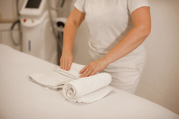 woman hands folding clean towel on massage couch in spa salon