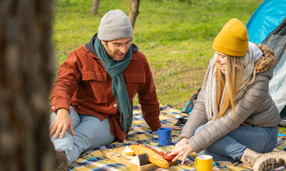 Campers sharing a spanish picnic lunch of bread, cheese, and sausage near their tent