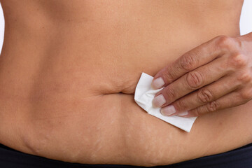 Hand holding a tissue near the navel for cleaning