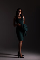 Elegant woman in green dress with jacket in studio light at night