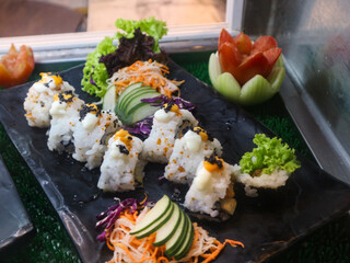 A platter of freshly prepared sushi rolls, beautifully garnished and ready to be served