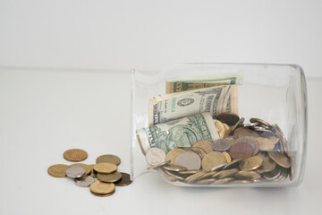 Glass jar with coins and dollar bills, concept of savings and personal finance