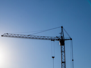 Construction Crane Silhouettes Against Clear Blue Sky During Daylight