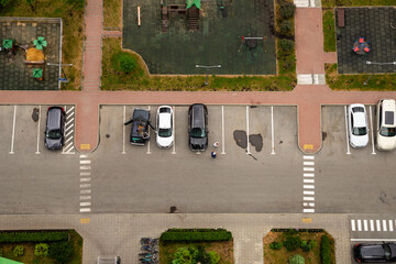 Busy parking lot with cars parked in designated spaces during sunny day near playground. aerial view